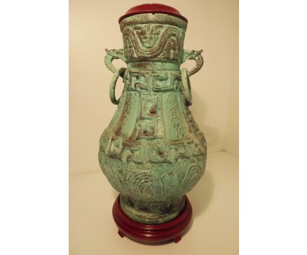 BR0010 Brons. Groen-bronzen pot/amphora met houten afdekplaatje en draken-handvaten met bronzen draagringen op houten voorgevormde voet (pot heeft geen bodem !). Hoogte 35 cm, diameter pot 18 cm, diameter voet 13 cm.