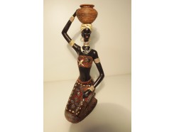 P1035181 Poly Africa. Gehurkte afrikaanse dame met pot op haar hoofd in traditionele kleding en sieraden. Jurk is bekleed met spiegeltjes in bloemmotief. 25 cm. hoog en 14 cm. diep.