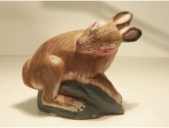 227-91 Steen. Gekleurd stenen konijn. L x H : 11 x 8 cm.
